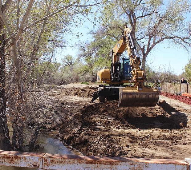 Heavy equipment digs out dirt to create a channel that to carry additional water past the Bafford Lane bridge to the Carson Sink.