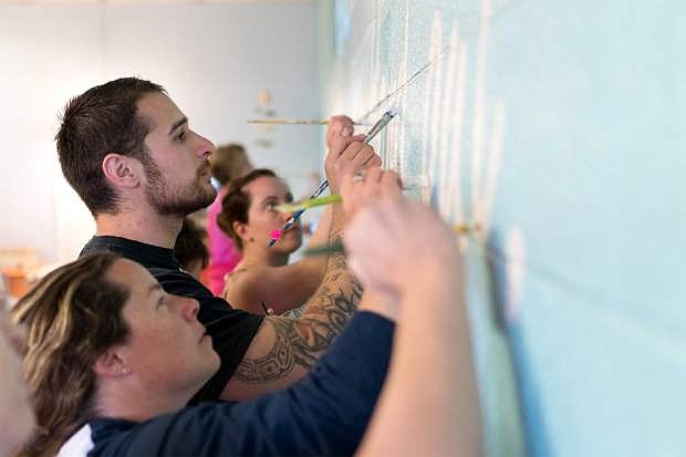 From left, Jennifer Budge, Max Macedo and other members of the Carson City Chamber of Commerce&#039;s 2017 Leadership Class paint a mural on the wall of the dining room at FISH on Thursday, May 3, 2017. The finished work will be unveiled during a celebration on Friday at 6 p.m. Photo by Cody Blue/Nevada Photo Source
