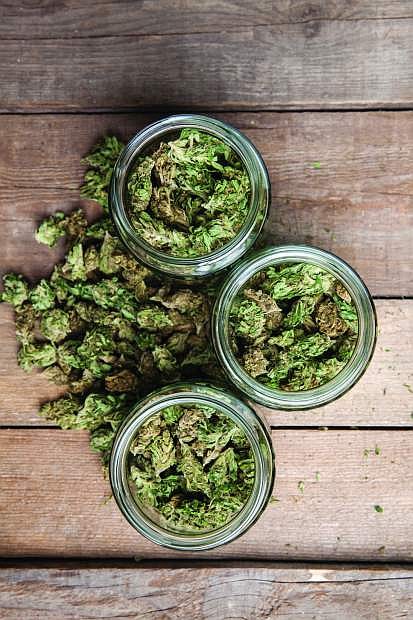 Marijuana buds in glass jars on wooden background