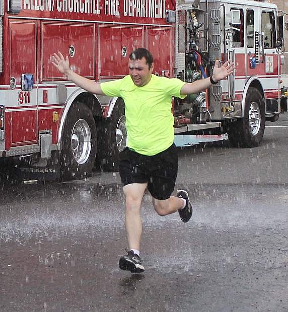 Sean Lacow runs through a spray of water as he homes to the finish of the Honoring American Heroes 5k.