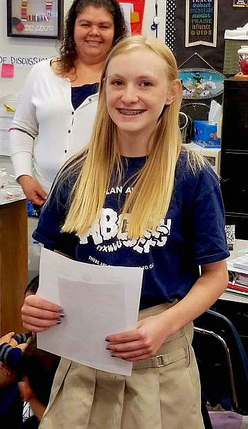 Oasis Academy student McKenna Jaques stands with her letter notifying the school of her winning essay; her English teacher Berenice de Leon, who submitted the student essays, is in the background.