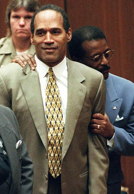 FILE - In this Oct. 3, 1995 file photo, attorney Johnnie Cochran Jr., right, holds onto O.J. Simpson as the not guilty verdict is read in a Los Angeles courtroom. Simpson, the former football star, TV pitchman and now Nevada prison inmate, will have a lot going for him when he appears before state parole board members Thursday, July 20, 2017, seeking his release after more than eight years for an ill-fated bid to retrieve sports memorabilia. (AP Photo/Pool, Myung J. Chun, file)