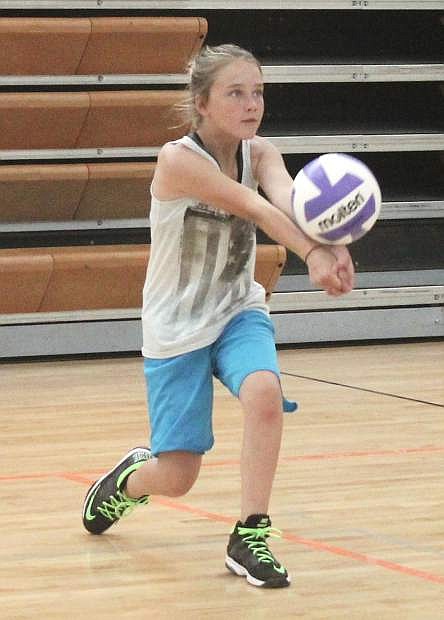 Ruby Peterson practices her serve as she waits her turn to scrimmage during the summer volleyball camp at the county gym.