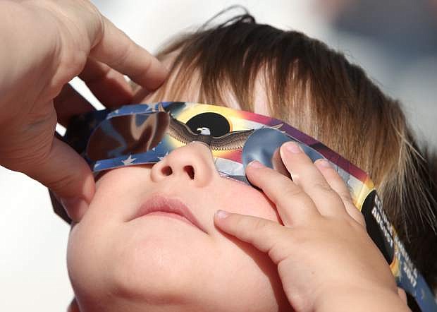 With the help from his mom 2-year-old Porter Caten views the solar eclipse on Monday morning.