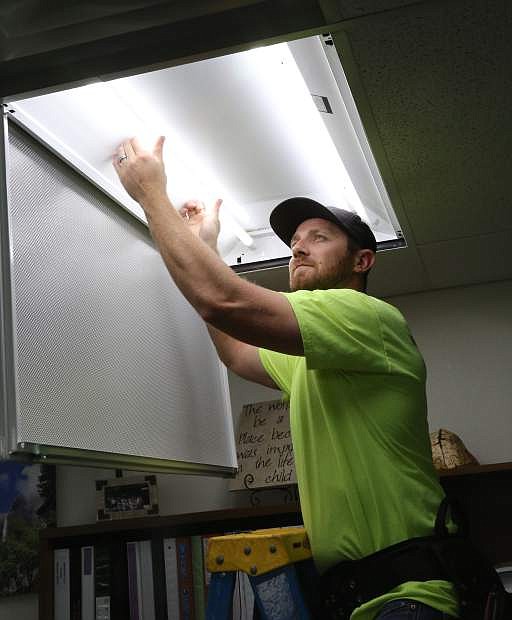 Electrician Colby Masters installs LED lighting in a classroom at Carson High School on Wednesday.
