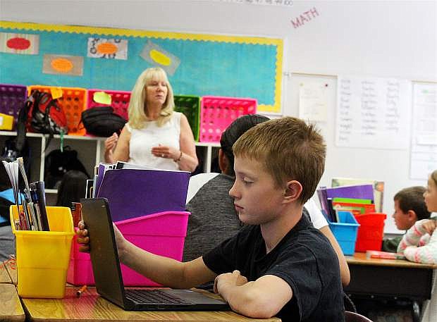 Adam Blunt, a fourth-grade student at Numa Elementary last year, studies a lesson from teacher Pat Moore on a laptop last spring.