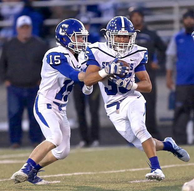 Jon Laplante hands the ball off to Kyle Rudy Friday night against McQueen in Reno.