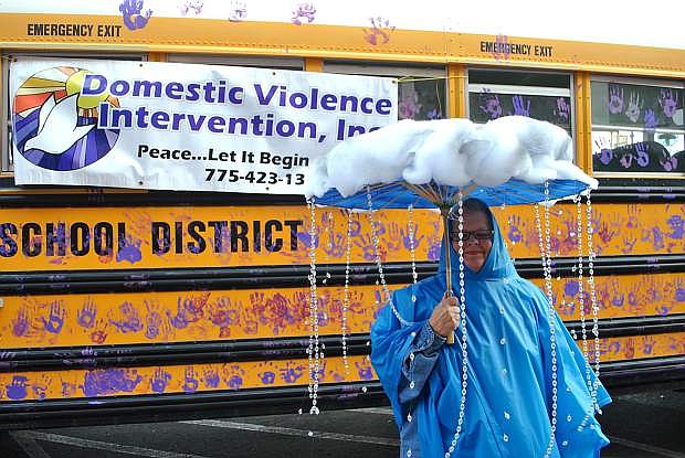 Karen Moessner, director at Domestic Violence Intervention, stands peacefully in her last year&#039;s Halloween attire for the downtown &quot;Trick-or-Treat&quot; event, posing in front of the CCSD school bus decorated with student handprints teaching &quot;hands are not for hitting.&quot;