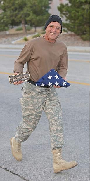 Ken Curtzwiler carries a flag and plaque in rememberance of his daughter SFC Miranda McElhiney during the IHOP Memorial Run/Walk Wednesday morning.
