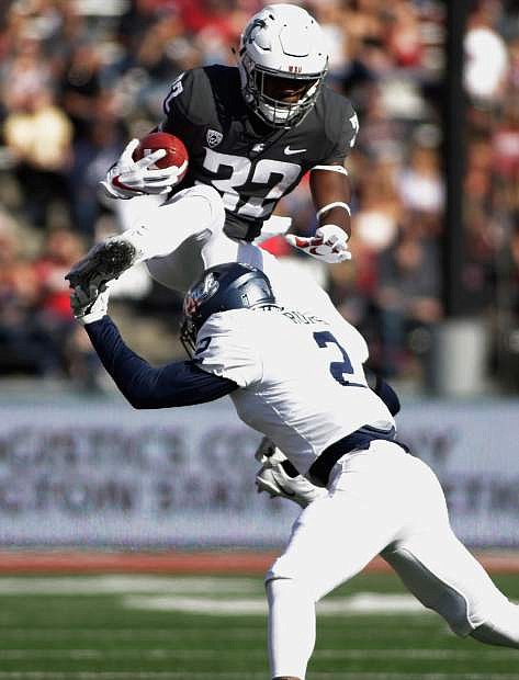 Washington State running back James Williams (32) leaps over Nevada defensive back Asauni Rufus (2) during the first half Saturday.