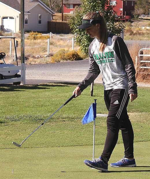 Glenda Lee measures out the distance from her putting marker to the hole during a Lady Wave golf team practice.