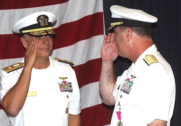 Outgoing commander of the Naval Aviation Warfighting Development Center, Rear Adm. Mark Harris, right, salutes incoming commander, Rear Adm. Daniel Cheever.