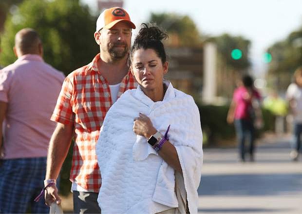 Melissah Burke and her husband Stephen, of Seattle, walk along the Las Vegas Strip near Mandalay Bay hotel and casino Monday, Oct. 2, 2017, in Las Vegas. The couple, who were attending the music festival last night where a mass shooting occurred, found refuge in a nearby apartment and casino. (AP Photo/Ronda Churchill)