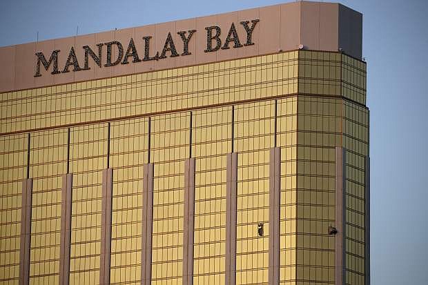 FILE - In this Monday, Oct. 2, 2017 file photo, drapes billow out of broken windows at the Mandalay Bay resort and casino on the Las Vegas Strip, following a deadly shooting at a music festival in Las Vegas. Two hotel employees had called for help and reported that gunman Stephen Paddock sprayed a hallway with bullets, striking an unarmed security guard in the leg, several minutes before Paddock opened fire from the resort on a crowd below at a musical performance, killing dozens of people and injuring hundreds. (AP Photo/John Locher, File)
