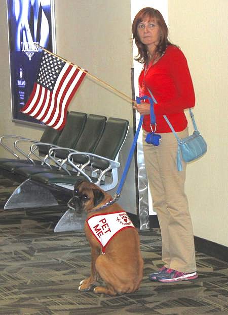 Fernley resident Julianne Collmee holds a flag while waiting for returning Honor Fligth veterans with her boxer, Allie,