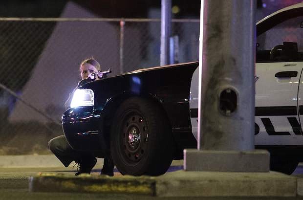 A police officer takes cover behind a police vehicle during a shooting near the Mandalay Bay resort and casino on the Las Vegas Strip, Sunday, Oct. 1, in Las Vegas. (AP Photo/John Locher)