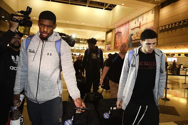 UCLA basketball players Cody Riley, left, LiAngelo Ball, right, and Jalen Hill, background center, are surrounded by the media as they leave the Los Angeles International Airport on Tuesday, in Los Angeles.