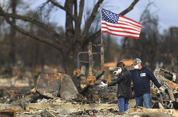 FILE - In this Oct. 20, 2017, file photo, Linda and Jason Miller look over their burned home in Coffey Park in Santa Rosa, Calif. California Gov. Jerry Brown joined lawmakers to request $7.4 billion in federal funding for wildfire relief and recovery efforts following a deadly cluster of fires that that tore through the heart of the state&#039;s wine country, killing more than 40 people and leaving thousands without housing. (Kent Porter/The Press Democrat via AP, file)