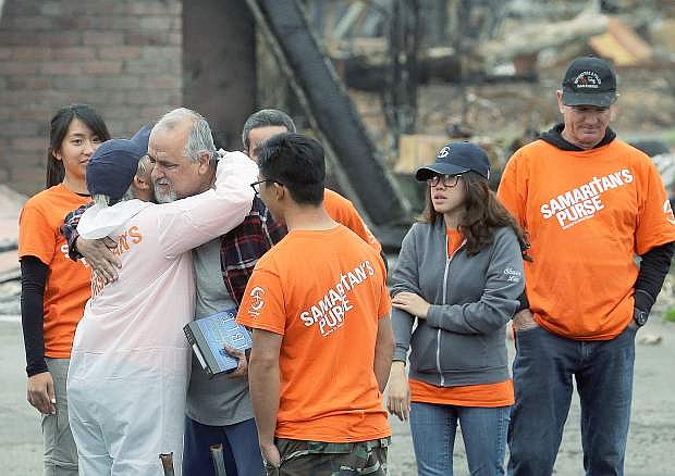 Larry Keyser, third from left, hugs volunteers from Samaritan&#039;s Purse disaster relief after they helped him sift through remains of his family&#039;s home destroyed by fires in the Coffey Park area of Santa Rosa, Calif., Wednesday, Nov. 8, 2017. Rumbling front loaders began scraping up the ash and rubble of nearly 9,000 destroyed homes and other structures in Northern California this week as the U.S. Army Corps of Engineers launched a new phase of the largest wildfire clean-up in the state&#039;s history.