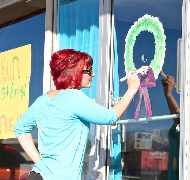 Owner of Absolute Hair on Stewart St., Angelica Leisle, finishes painting a wreath on her front door Wednesday.