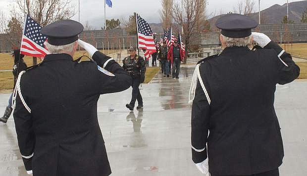 Two members of the Nevada Veterans Coalition salute as the Patriot Guard marches to the pavilion with U.S. flags.