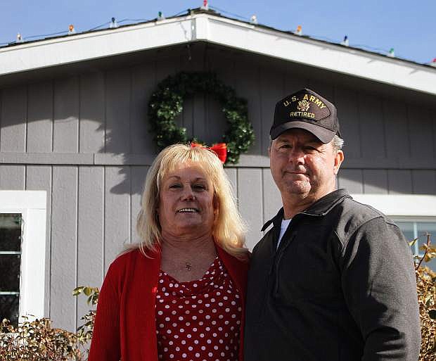 Bonnie and Stan Johnson smile in front of their home, newly decked out in Christmas cheer.
