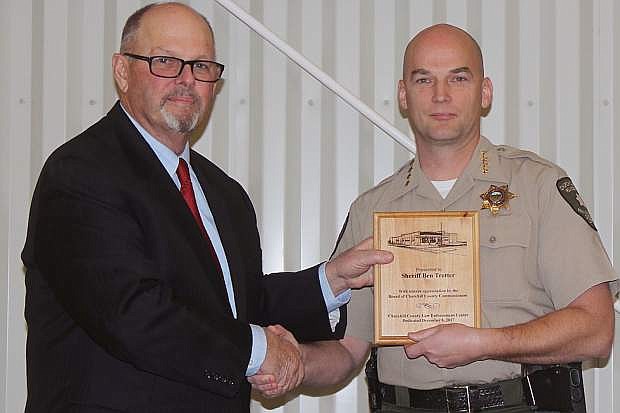 Sheriff Ben Trotter, right, received a plaque honoring him for his work on the new law enforcement center from Commissioner Pete Olsen. Trotter has announced he will not seek a third term as sheriff but will file, instead, to run for justice of the peace.
