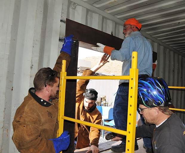 From left, Michael Varner, Charles Carnevale and Eric Forstrom assist Masih Madani, top right, put in a window frame on the home he is building out of a shipping container as part of a welding class project at Western Nevada College.