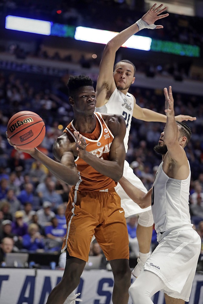Texas forward Mohamed Bamba passes under pressure from Nevada guard Kendall Stephens (21) and forward Caleb Martin, right, in the first half of a first-round game of the NCAA college basketball tournament in Nashville, Tenn., Friday, March 16, 2018. (AP Photo/Mark Humphrey)