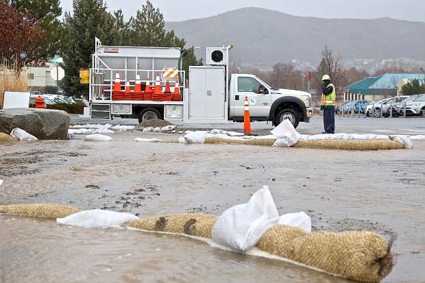 A Carson City Public Works employee makes a phone call as water flows towards the intersection of Rhodes St. and S. Curry during a storm in March. The Board of Supervisors discussed the storm water plan on Thursday.