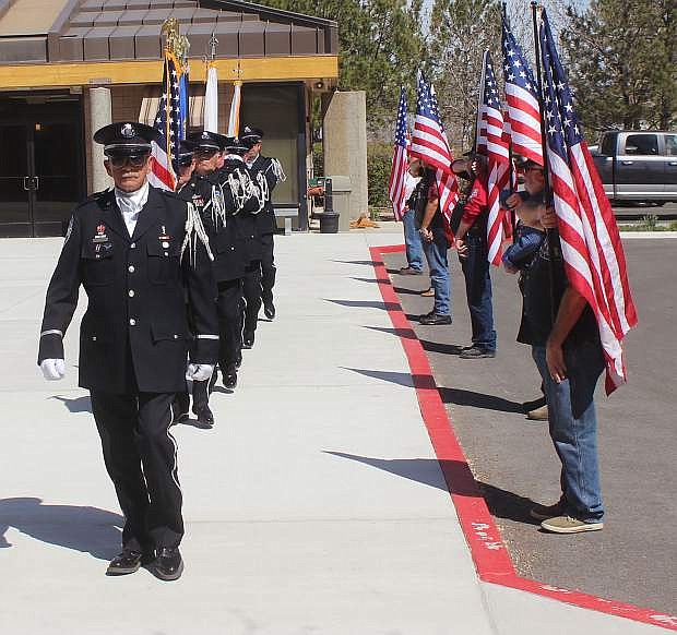 The Nevada Veterans Coalition Honor Guard marches past volunteers holding the U.S. flag.