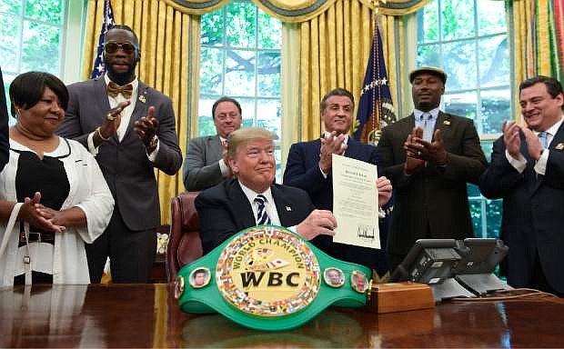 President Donald Trump center, posthumous pardons Jack Johnson, boxing&#039;s first black heavyweight champion, during an event in the Oval Office of the White House in Washington, Thursday, May 24, 2018. Trump is joined by, from left, Linda Haywood, who is Johnson&#039;s great-great niece, heavyweight champion Deontay Wilder, Keith Frankel, Sylvester Stallone, former heavyweight champion Lennox Lewis, and World Boxing Council President Mauricio Sulaiman Saldivar. (AP Photo/Susan Walsh)