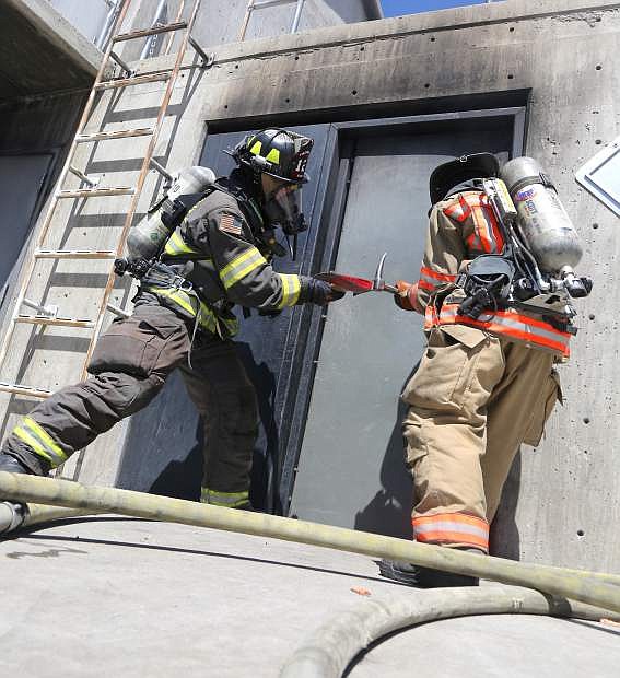 Firefighters train to use and axe and pry bar to open a locked door on Monday during the fire academy.