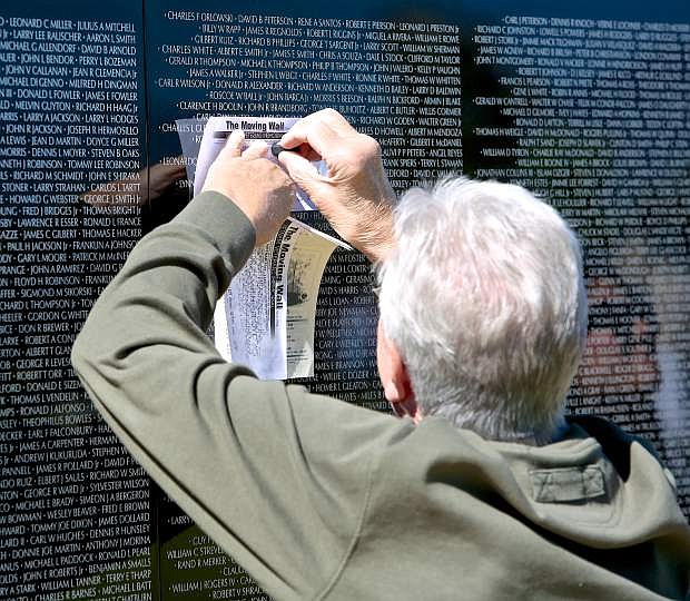 Mark Bowers of Carson City imprints members in his Vietnam War unit on a piece of paper from The Moving Wall Friday morning at Eastside Memorial Park in Minden.