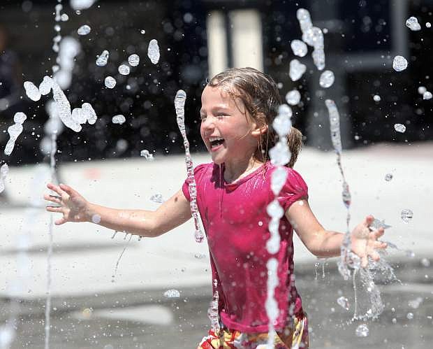 Alice Brown, 4, is all smiles as she cools off from the early summer heat playing in the splash pad at the Bob McFadden Plaza on Monday afternoon.