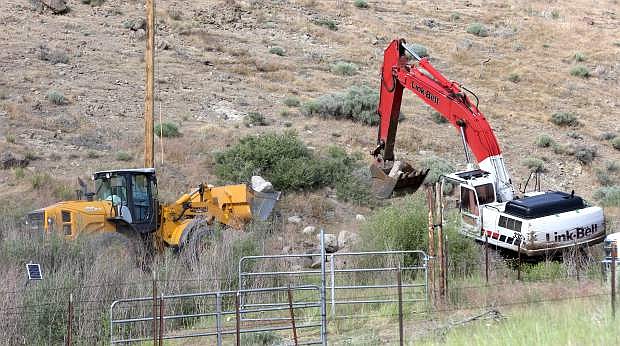 Crews work to fortify the earthen dam at Little Washoe Lake on Monday afternoon, which is in danger of a potential breaching.