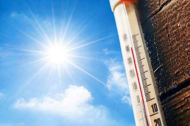 Thermometer with a high temperature reading on a scale, against a background of bright sun and a blue sky with clouds. The concept of hot, dangerous weather, global warming