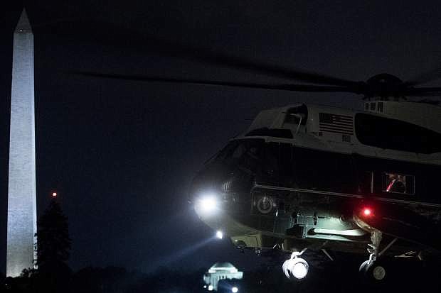 President Donald Trump with his red tie is visible in the window of Marine One as it touches down on the South Lawn of the White House in Washington, Monday, July 16, 2018, after a short helicopter ride from Andrews Air Force Base, Md. Trump returns following a meeting with Russian President Vladimir Putin in Helsinki, Finland. (AP Photo/Andrew Harnik)
