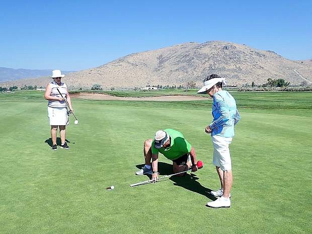 Pat Gilbert and Beth White look on as Beth Juri pool putts one in the hole at Eagle Valley Golf Course.