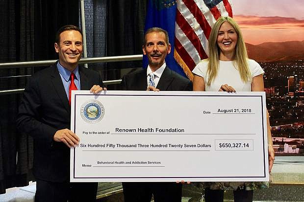 Nevada Attorney General Adam Laxalt, Renown Health President and CEO Dr. Anthony Slonim, and philoanthropist and Transforming Youth Recovery Founder Stacie Mathewson pose with a check for $650,000 in restitution funds that will go to a new health and addiction center in Reno.