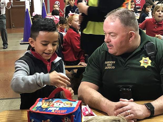 Carson City Deputy Sheriff Jarrod Adams, a school resource officer assigned to Seeliger Elementary School, sits with kindergartener Mathew Luna Mora Thursday during the campus&#039; first &quot;Thanksgiving with a Hero&quot; event in its cafeteria.