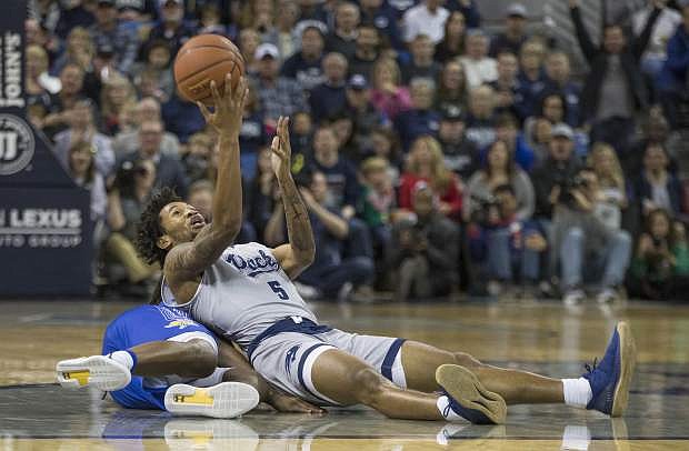 Nevada guard Nisre Zouzoua (5) passes the ball from the seat of his pants against South Dakota State in the second half of an NCAA college basketball game in Reno, Nev., Saturday, Dec. 15, 2018. (AP Photo/Tom R. Smedes)