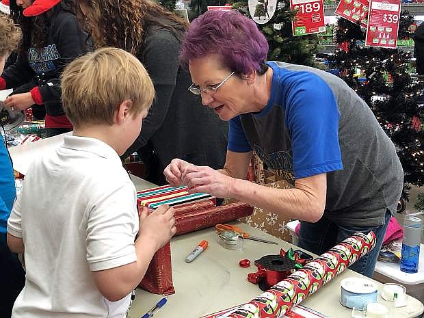 Donna Redfern, a Western Nevada College volunteer, helps Cory of Seeliger Elementary School wrap his gifts at the 15th annual &quot;Holiday with a Hero&quot; event at the Carson City Walmart on Wednesday.