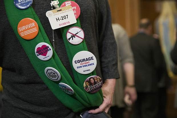 Sandy Phillips, whose daughter Jessi Ghawi was killed in the Aurora, Colo., movie theater shooting, wears a collection of buttons on her daughter&#039;s scarf before a news conference to announce the introduction of bipartisan legislation to expand background checks for sales and transfers of firearms, on Capitol Hill, Tuesday, Jan. 8, 2019 in Washington. (AP Photo/Alex Brandon)