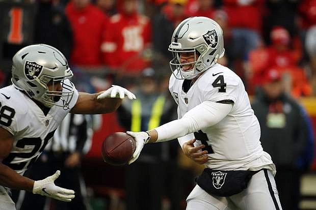 Oakland Raiders quarterback Derek Carr (4) hands the ball off to running back Doug Martin (28) during the first half of an NFL football game against the Kansas City Chiefs in Kansas City, Mo., Sunday, Dec. 30, 2018. (AP Photo/Charlie Riedel)