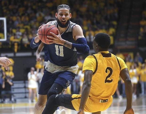 Nevada forward Cody Martin (11) charges forward past Wyoming forward AJ Banks during the first half of an NCAA college basketball game, Saturday, Feb. 16, 2019, in Laramie, Wyo. (AP Photo/Jacob Byk)
