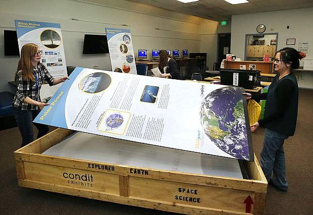 Creative Learning Manager Maria Klesta, left, and Librarian Vanna Bells set up the Explore Earth: Our Changing Planet exhibit at the Carson City Library on Friday. The traveling exhibit featuring earth science topics is free and open to the public during library hours.