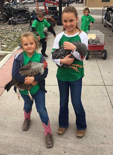 Macady Bogdanowicz, left, and Paige Frey carry their chickens when they Walked the Town to seek support for the annual Churchill County Junior Livestock Show and Sale.