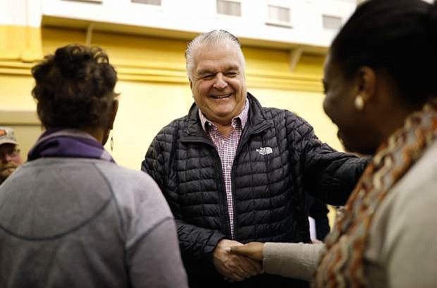 File - In this Jan. 4, 2019, file photo, Nevada Gov.-elect Steve Sisolak, center, shakes hands with Laniesha Dawson, right, at an International Alliance of Theatrical Stage Employees union hall in Las Vegas. For decades, enacting collective bargaining for state workers has remained an elusive goal of supportive Nevada lawmakers. But Democrats this session appear poised to make it a reality, with strong majorities in both legislative chambers and the first Democratic governor in two decades. (AP Photo/John Locher, File)