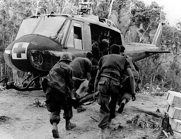A MEDEVAC (medical evacuation) crew moves an injure soldier to the Huey helicopter.